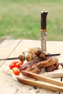 Grilled ribs and champignon on skewer served with fresh cucumber and tomato on wooden table outdoor