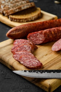 Closeup view of smoked pork sausage rings on wooden cutting board on kitchen table