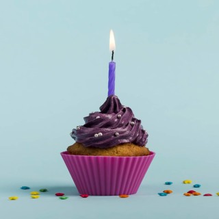 Purple burning candles decorative muffins with colorful star sprinkles against blue backdrop