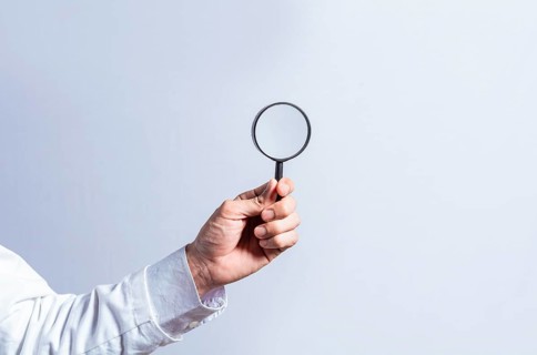 Man hand holding magnifying glass on white background. Hand holding magnifying glass looking for something with space for text