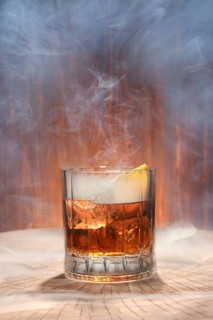 Cocktail with smoked whisky and orange bitter on the lid of the barrel