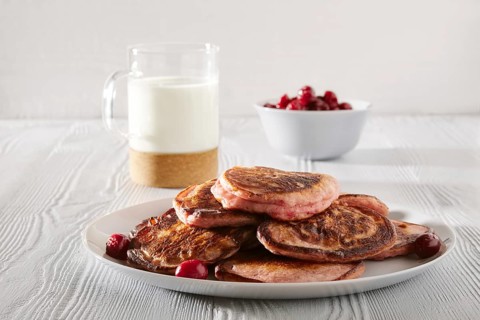 Pancakes with cherry and glass of milk on white kitchen table