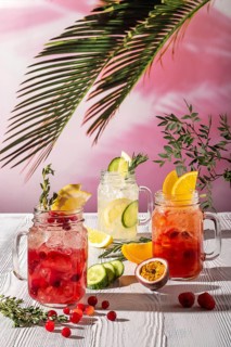 Different lemonades with different fruits and syrups on wooden table under morning sun