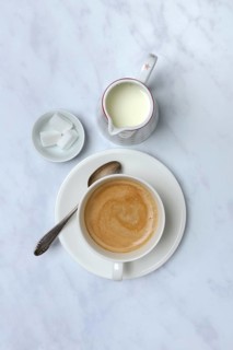 Cup with coffee and pot of milk