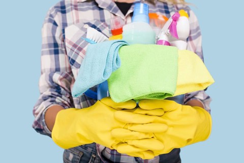 Mid section cleaner holding bucket with cleaning products wearing yellow gloves