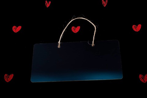 Rectangular shaped black notice board and red hearts on black background