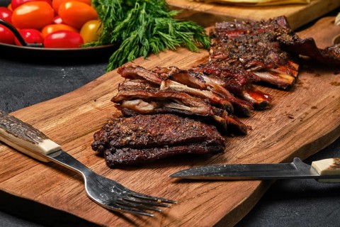Top view of grilled lamb breast ribs on wooden cutting board