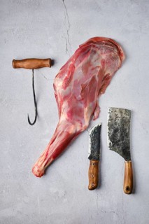 Overhead view of raw fresh deer leg with spice and herb over concrete background