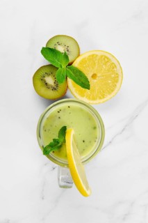 Overhead view of kiwi and lemon smoothie with mint on marble background