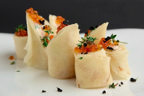 Close up view of pancakes with salmon and caviar on big white plate