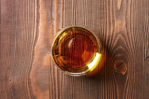 Top view of snifter glass with pure whiskey on dark wooden table