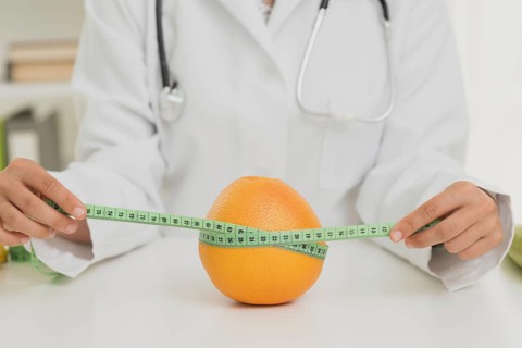 Close up nutritionist measuring orange