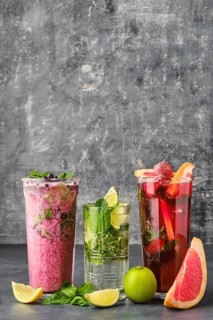 Three glasses with fruit refreshing drink on gray shabby background