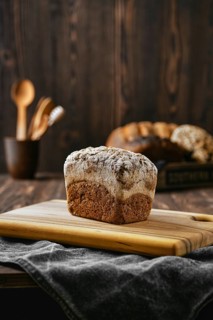 Loaf of artisan rye bread with flour topping on wooden cutting board