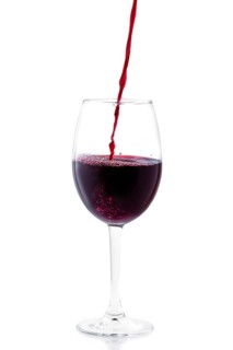 Pouring red wine in glass isolated on white background