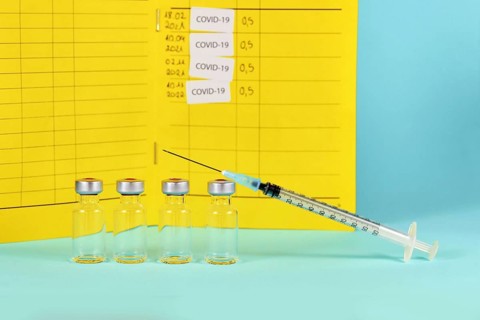 Corona booster vaccine concept with 4 vials with syringes and certificate of vaccination in background with copy space
