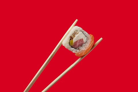 Holding roll with salmon and tuna with chopsticks