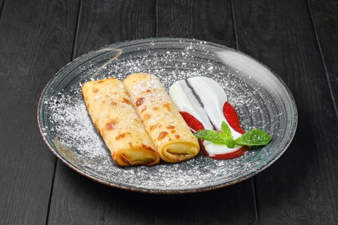 Thin crepe with ricotta and strawberry jam on a plate