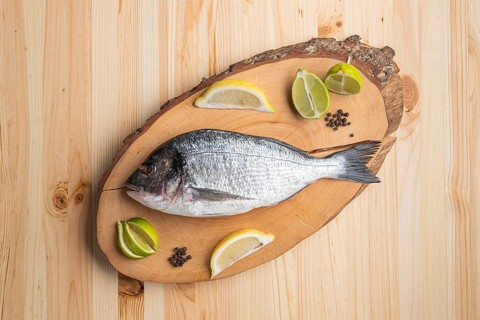 Fresh raw dorada on wooden cutting board
