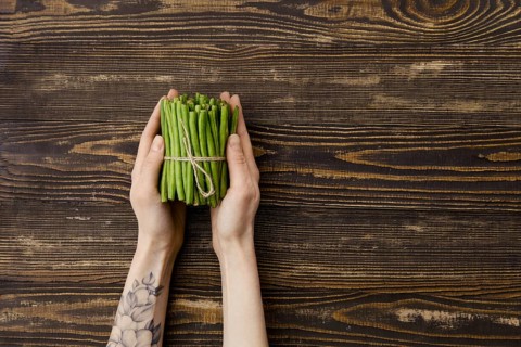 Overhead view of fresh green beans in hand over wooden background