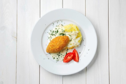 Top view of cutlet stuffed with cheese with mashed potato on white wooden table