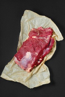 Overhead view of raw fresh beef neck on wrapping paper