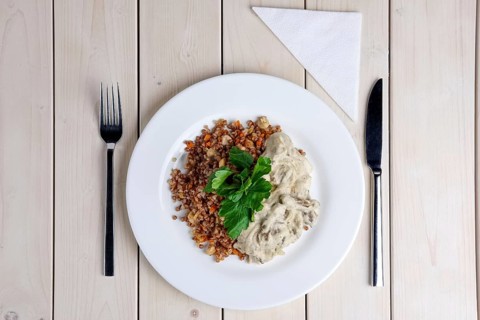 Top view of beef stroganoff with creamy onion sauce and buckwheat with fried mushrooms on served table