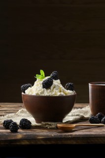 Dairy product cottage cheese and milk in brown ceramic bowl with spoon on wooden table