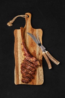 Tomahawk steak cut on slices on wooden board