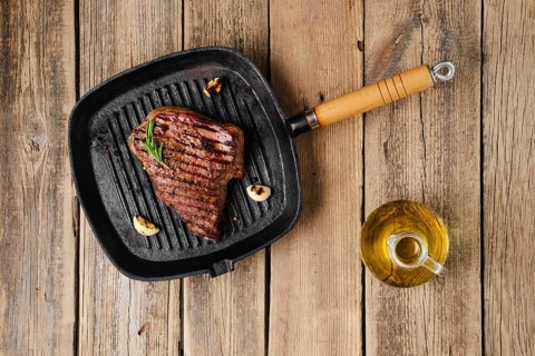 Overhead view of chuck eye steak fried on cast iron grill pan