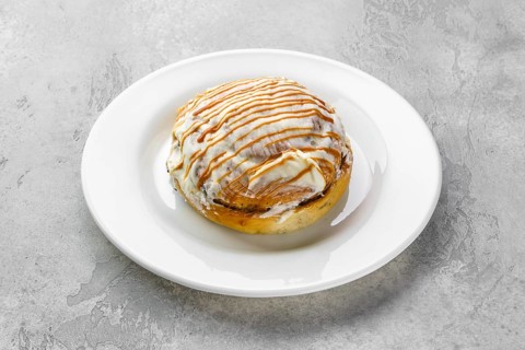 Fresh cinnamon bun with sugar icing and caramel