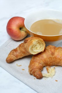 Coffee with milk in bowl and croissant