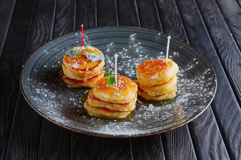 Plate with heap of fritters decorated with honey