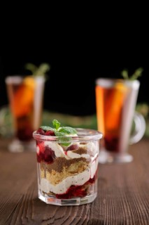 Delicious tiramisu dessert with cherry and citrus tea on dark wooden background