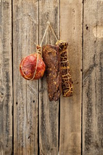 Assortment of dried meat and sausages hanging on a barn wall