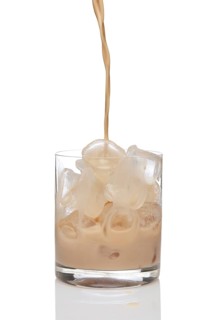 Irish creme liqueur pouring in a glass full of ice