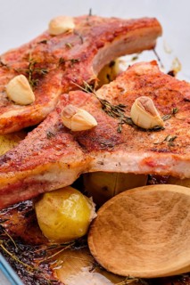 Steak with bone and potato baked in oven in a roasting pan with garlic and thyme