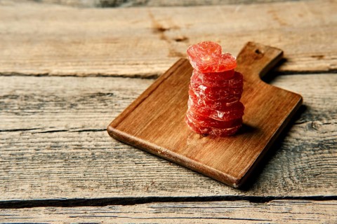 Close up view of smoked dried stacked slices of turkey sausage on wooden cutting board