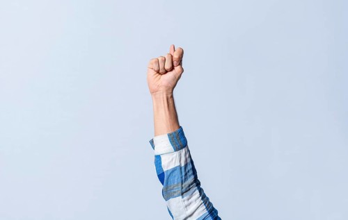 Hand gesturing the letter T in sign language on an isolated background. Man's hand gesturing the letter T of the alphabet isolated. Letter T of the alphabet in sign language