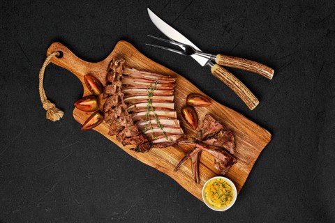 Overhead view of grilled ribs of lamb on a plate with spicy sauce