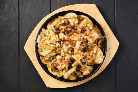 Overhead view of slices of eggplant baked with champignon and cheese in cast iron skillet
