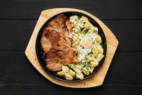 Top view of fried pork t-bone chop with potato and egg on a plate