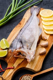 Raw fresh haddock carcass on wooden cutting board