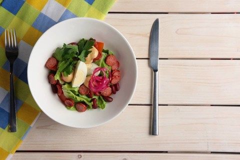 Salad with smoked sausage and egg. Top view of served table