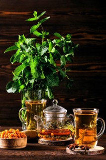 Low key photo of hot herbal tea with sea buckthorn and mint on wooden table