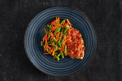 Top view of fried fillet of white fish with cheese topping served with green bean and spicy carrot