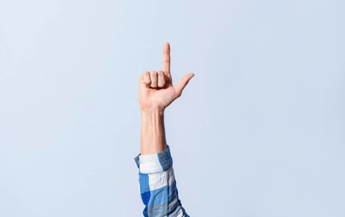 Hand gesturing the letter L in sign language on an isolated background. Man's hand gesturing the letter L of the alphabet isolated. Letters of the alphabet in sign language
