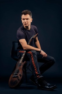 Low key portrait of musician sitting on chair with guitar