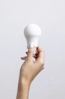 Front view hand holding light bulb with copy space