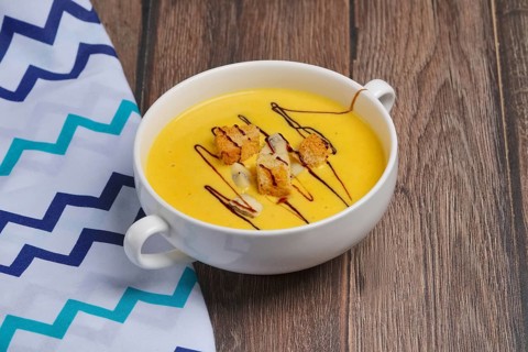 Plate of pumpkin soup on wooden table